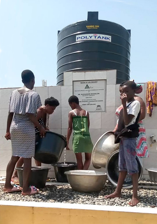 Réservoir d'eau - Extraction d'eau dans des conteneurs Un groupe d'enfants extrait de l'eau d'un réservoir, divers conteneurs, vêtements clairs, environnement ensoleillé.