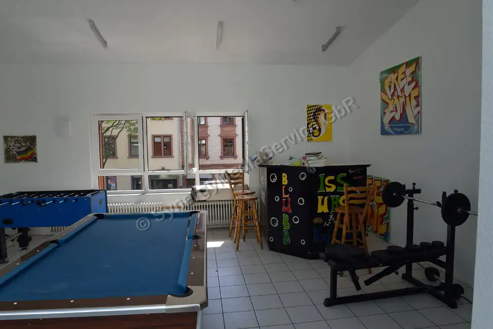 Salle de loisirs avec billard et équipements de fitness Salle de loisirs lumineuse avec billard, baby-foot, équipements de fitness et bar, grande baie vitrée.